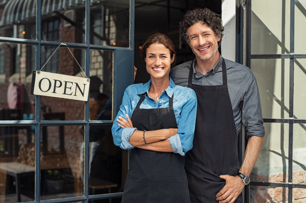 Two,Cheerful,Small,Business,Owners,Smiling,And,Looking,At,Camera Business occupation